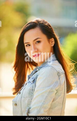 Beautiful attractive young brunette standing outdoors on summer day and smiling at camera Stock Photo