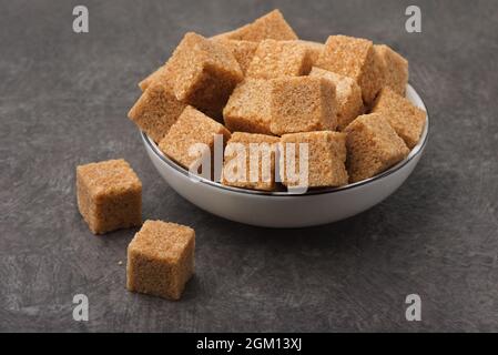 Brown unrefined cane sugar cubes on dark background Stock Photo