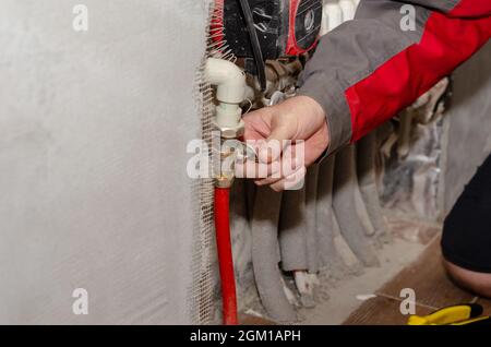A man opens a gate valve on the piping of a space heating system Stock Photo