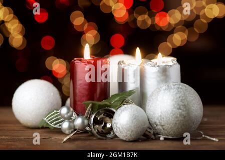 Burning Christmas candles and ornaments over blurred festive lights on dark background Stock Photo