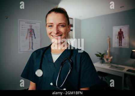 Caucasian female nurse smiling standing in doctors office  Stock Photo
