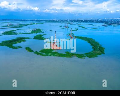 DHAKA, BANGLADESH - SEPTEMBER 16, 2021: Aerial view of a Chimney from local Brick Factory flooded by monsoon rains near Savar, Dhaka, Bangladesh. Hundreds of brick factories appear to have nearly disappeared under water following severe flooding. The buildings were covered with water due heavy rains during entire monsoon season. Workers were able to save thousands of bricks - but many were lost to the 20 ft deep floodwater. On September 16, 2021 in Dhaka, Bangladesh. (Photo by Mustasinur Rahman Alvi/ Eyepix Group) Stock Photo