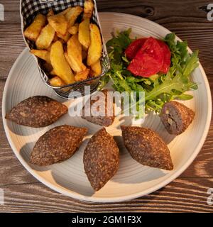 Traditional kebbe and pita bread on big round plate in lebanese restaurant Stock Photo