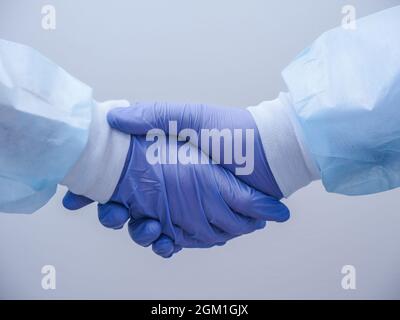 Handshake of two doctors' hands in medical gloves Stock Photo