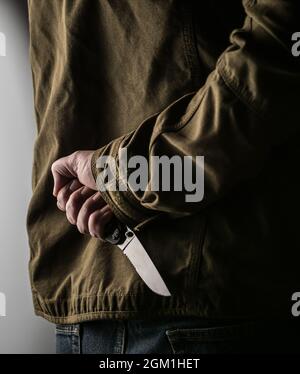 Man hiding a knife behind his back Stock Photo