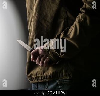 Man hiding a knife behind his back Stock Photo
