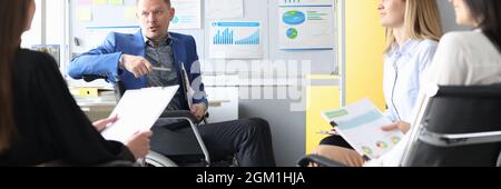 Business coach in wheelchair conducts business meeting of employees Stock Photo