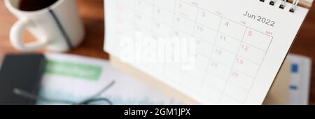 Calendar for June calculator and cup of tea is on table Stock Photo