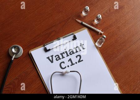 Medical concept. Top view of paper clipboard with text Covid-19 variant C.1.2, stethoscope, glass vial and syringe. Stock Photo