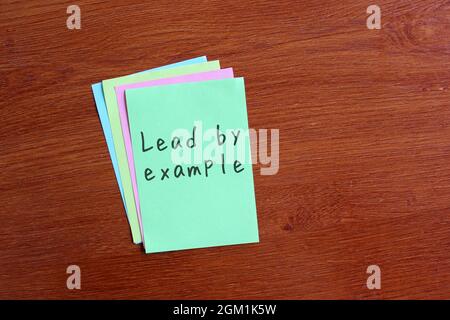 Motivational quotes concept. Lead by example written on notepaper Stock Photo