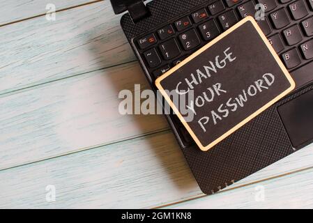 Technology concept. Mini blackboard with text CHANGE YOUR PASSWORD on laptop. Stock Photo