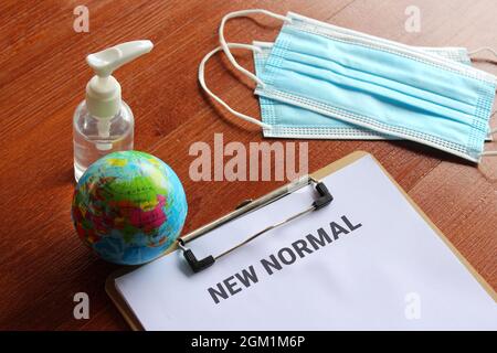 Medical and healthcare concept. Facemask, hand sanitizer, earth globe and paper clipboard with text NEW NORMAL Stock Photo