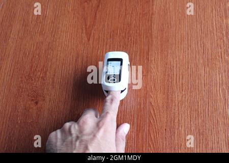 Selecting focus image of finger using pulse oximeter on wooden table. Medical and healthcare concept Stock Photo