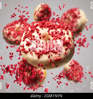 Flying donuts glazed with white chocolate decorated with lyophilized strawberries on red background Stock Photo