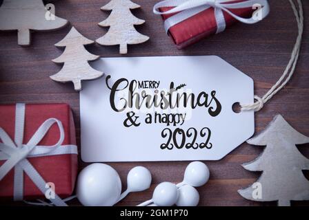 One Label With English Calligraphy Merry Christmas And Happy 2022. Christmas Decoration Like Gifts And Trees. Wooden Background Stock Photo