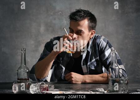 Man drinking alcohol and smoking cigarette while sitting at table Stock  Photo - Alamy