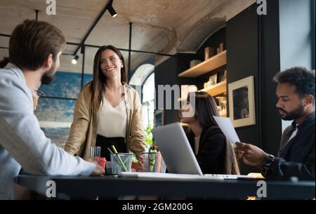 Female executive leader talking to happy diverse employees group at corporate office briefing Stock Photo