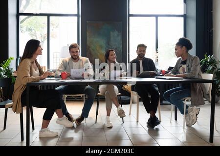 Happy Coworkers Working Together Discussing Project Sitting At One Desk In Modern Office. Panorama Stock Photo