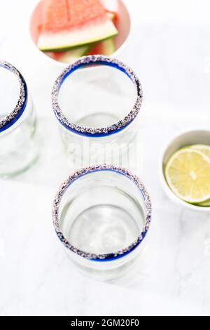 Garnishing edged of the glass with salt for frozen watermelon margarita. Stock Photo