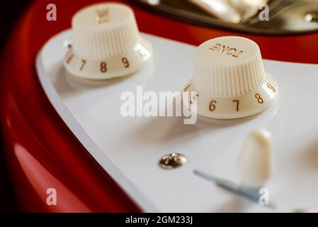 Detail of the volume and tone knobs of a red electric guitar Stock Photo