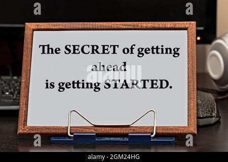 Motivational quote inspiring success. The secret to getting ahead is getting started written in a wooden frame against the background of the computer Stock Photo