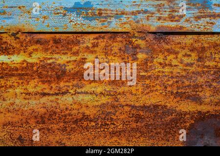 Old rusty metal door, painted blue which becomes orange from rust. Texture of cracks and peels paint Stock Photo