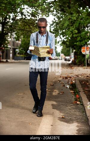 young tourist man with black sunglasses tenant and reading a map of the city in hand Stock Photo