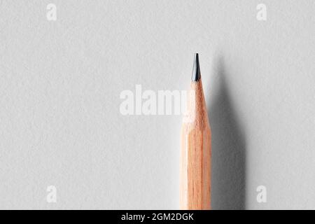 Close up of sharp wooden pencil point on white background with copy space. Back to school concept. Stock Photo