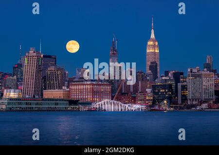 Moon Over NYC - The midtown Manhattan New York City skyline with the Empire State Building (ESB) and a super moon rising above the new Thomas Heatherw Stock Photo
