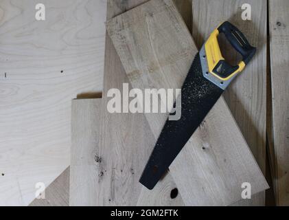 A Black Handsaw on White Oak Floor Boards Stock Photo