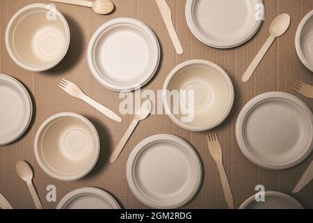 eco friendly disposable tableware. paper dishware and wooden cutlery on cardboard background. top view Stock Photo