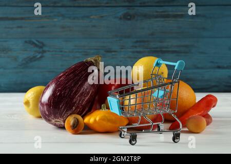 Shop cart, vegetables and fruits on wooden table Stock Photo