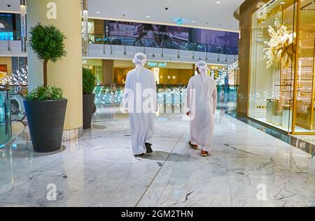 DUBAI, UAE - MARCH 7, 2020: Two men in traditional white Arabic attire walk the vestibule of Dubai Mall, on March 7 in Dubai Stock Photo