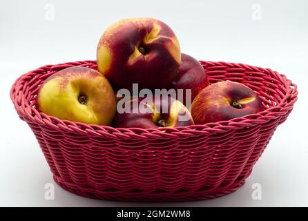 Ripe peaches in a red basket isolated on white background Stock Photo