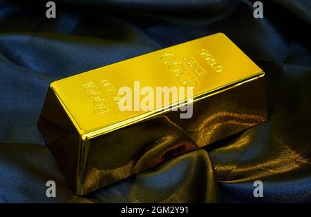 Gold bar 1 kg on smooth elegant black silk fabric luxury cloth background Stock Photo