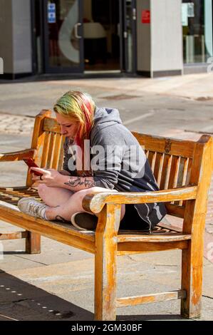Dundee, Tayside, Scotland, UK. 16th Sep, 2021. UK weather: Warm mid September sunshine across North East Scotland with temperatures reaching 19°C. A young woman spending the day out enjoying the glorious warm sunny weather whilst texting messages on her mobile phone in Dundee city centre. Credit: Dundee Photographics/17�Թ����� Live News Stock Photo