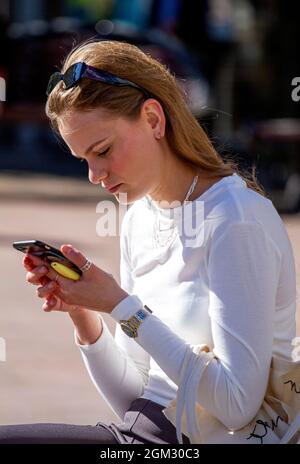 Dundee, Tayside, Scotland, UK. 16th Sep, 2021. UK weather: Warm mid September sunshine across North East Scotland with temperatures reaching 19°C. A glamorous young Polish woman spending the day out enjoying the glorious warm sunny weather whilst texting messages on her mobile phone in Dundee city centre. Credit: Dundee Photographics/17�Թ����� Live News Stock Photo