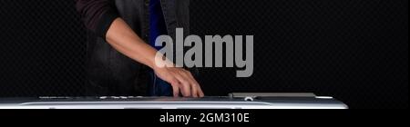 Closeup musician's hand playing on a music keyboard player in front of black soundproofing walls. Musician producing music in professional recording s Stock Photo