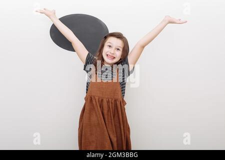 portret emotional 7 year old girl on white background. baby girl shows the emotion of fun. mock up on wall and raises his hands up. selective focus. Stock Photo