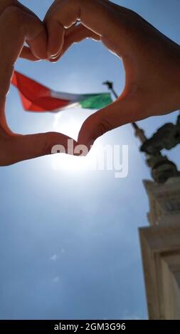 Gesture made by hands showing symbol of heart and love over national italy flag. woman showing her love for the Italian flag Stock Photo