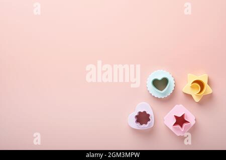 Multicolored cookie molds cutters on pink background with copy space for your advertisement and text. Baking concept. Flat lay. Mock up. Stock Photo