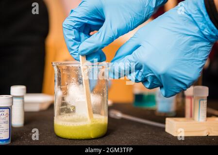 Latex gloved hand pour a beaker of liquid during a science experiment in school lab. Stock Photo