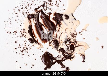 Dirty white background with melted chocolate and spilled cream, residue of chocolate preparation on kitchen table. Stock Photo