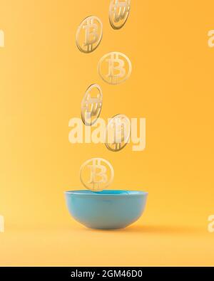 Bitcoins falling in blue bowl against orange background. Bitcoin wealth concept. Mining or blockchain technology for cryptocurrency concept. Abstract Stock Photo