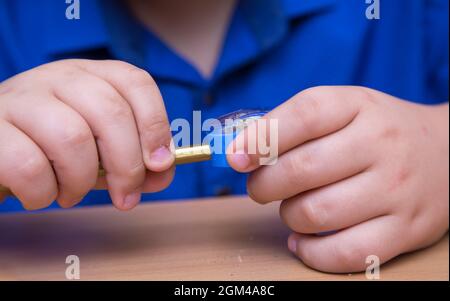 Close-up hands of a student turn a pencil in a sharpener. A schoolboy performs a task at the workplace. The concept of children's education, teaching knowledge, skills and abilities. Stock Photo