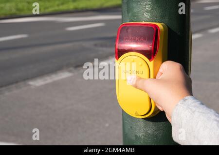 Child hand presses a yellow device with a button on demand on traffic light Stock Photo