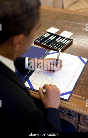 President Barack Obama signs a bill in the Oval Office,  August 7, 2009.    (Official White House Photo by Pete Souza) This official White House photograph is being made available only for publication by news organizations and/or for personal use printing by the subject(s) of the photograph. The photograph may not be manipulated in any way and may not be used in commercial or political materials, advertisements, emails, products, promotions that in any way suggests approval or endorsement of the President, the First Family, or the White House. Stock Photo