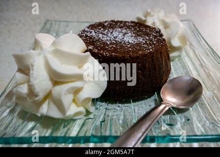 small chocolate cake topped with powdered sugar and whipped cream Stock Photo