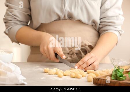 Woman preparing tasty gnocchi at table in kitchen, closeup Stock Photo