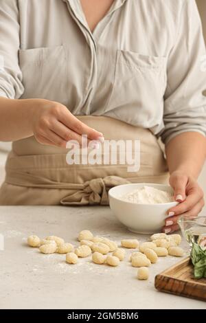 Woman preparing tasty gnocchi at table in kitchen, closeup Stock Photo